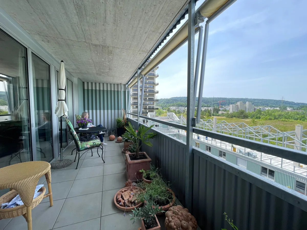 Ihre 2,5-Zimmer-Wohnung verfügt über einen geräumigen Balkon.  Bild von einem Balkon, in einem Stuhl sitzt eine Frau.